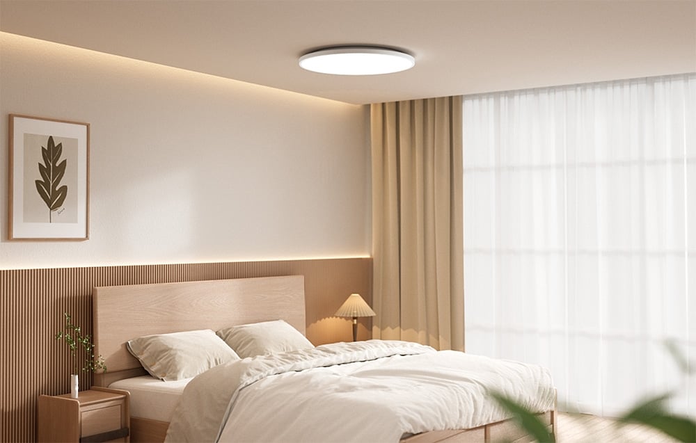 Jasna sypialnia z łóżkiem i włączoną inteligentną lampą sufitową eelight Mercury C300.