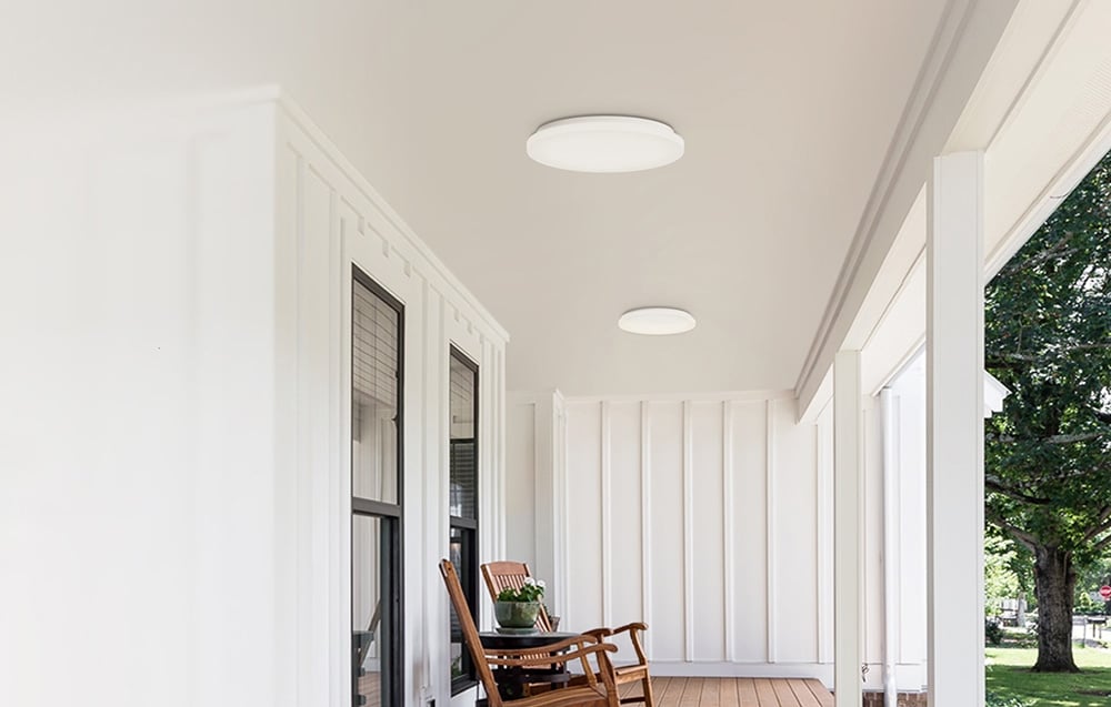 Dwie lampy sufitowe Yeelight MercuryE C300 zamontowane na zadaszonym ganku z drewnianą podłogą i krzesłem bujanym.