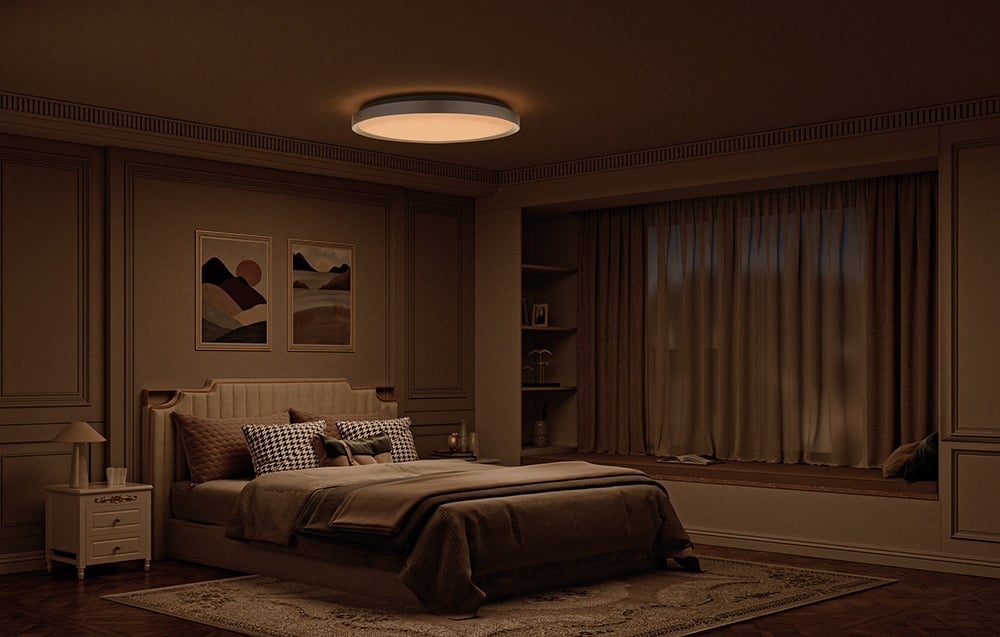 Przytulna sypialnia w ciepłej tonacji z łóżkiem i lampą Yeelight Jupiter D C500 świecącą miękkim, ciepłym światłem.