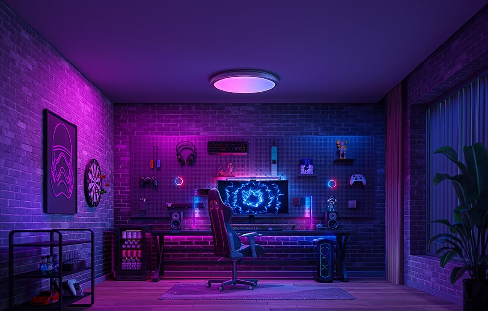 Pokój gamingowy z podświetleniem w kolorach fioletu i różu, z lampą Yeelight Jupiter D C500 nad stanowiskiem komputerowym.
