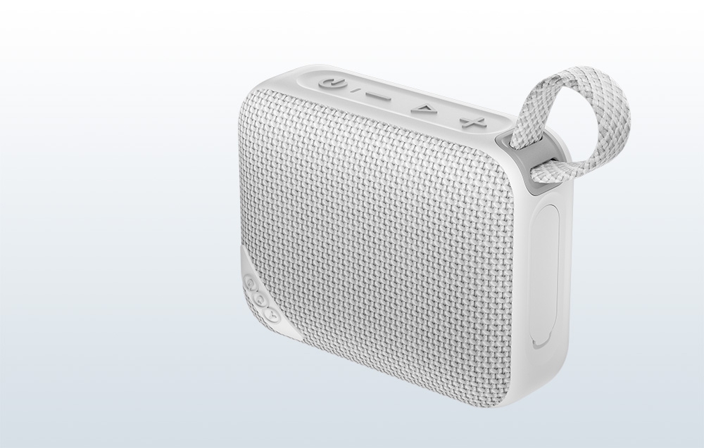 Szary głośnik z teksturowaną powierzchnią i uchwytem na jasnym tle