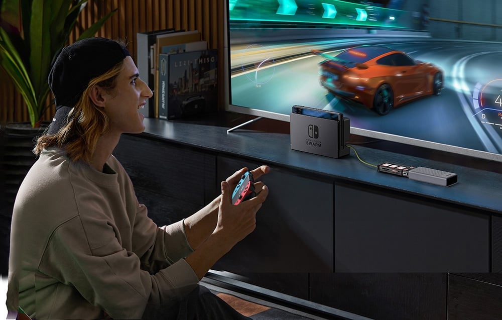 Mężczyzna gra na konsoli Nintendo Switch podłączonej do telewizora, trzymając kontroler