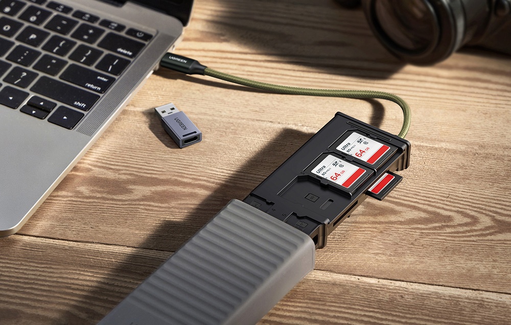 Zbliżenie na laptopa z podłączonym hubem USB, do którego włożone są trzy karty o pojemności 64 GB