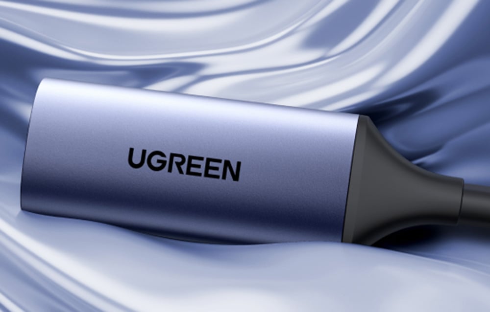 Close-up of the Ugreen CM629 video capture card lying on a light blue fabric.