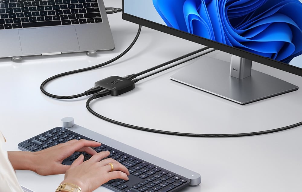 Osoba korzystająca z klawiatury, obok przełącznik Ugreen AW700 podłączony jest do laptopa i monitora.