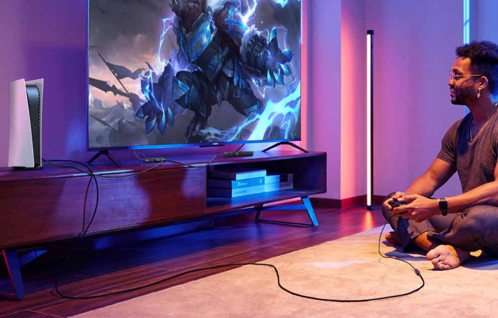 Mężczyzna grający w grę na konsoli, do której podłączony jest przełącznik Ugreen AW700.