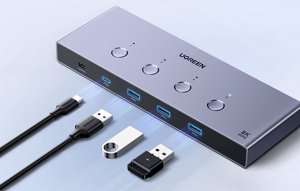 Comutator KVM UGREEN cu patru porturi și butoane lângă cabluri și pendrive-uri