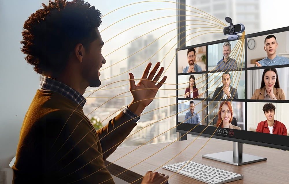 Mężczyzna prowadzący wideokonferencję z grupą ludzi, na jego monitorze znajduje się kamera Ugreen CM831.