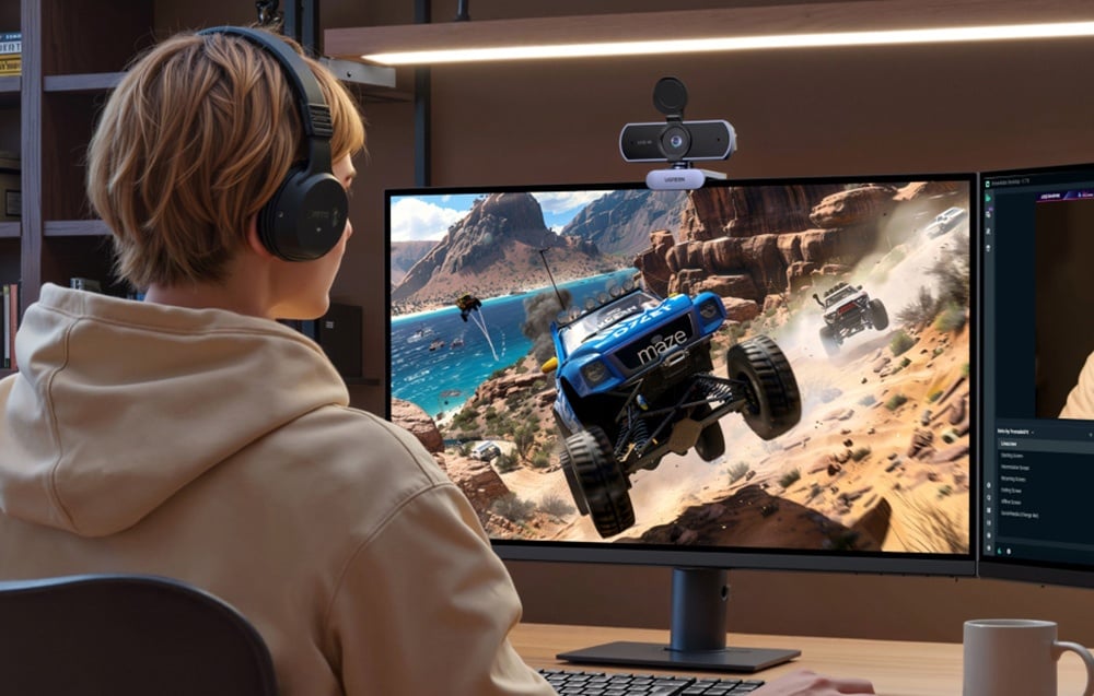 Mężczyzna w beżowym swetrze gra w grę komputerową, na jego monitorze stoi kamera Ugreen CM831.