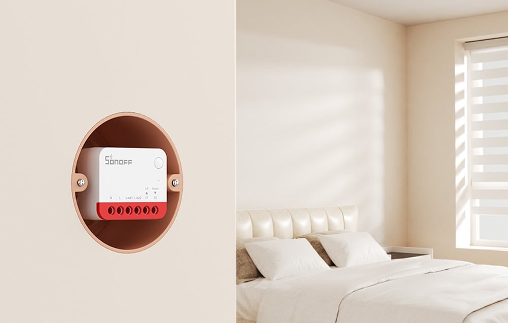 Moduł sterujący SONOFF umieszczony w okrągłej obudowie na ścianie sypialni z białym łóżkiem i żaluzjami okiennymi.