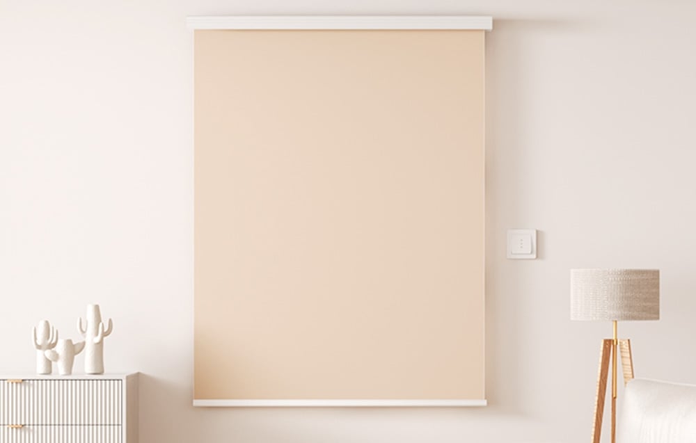 Beżowa roleta okienna w salonie z białą ścianą, lampą na drewnianej podstawie i dekoracyjnymi kaktusami