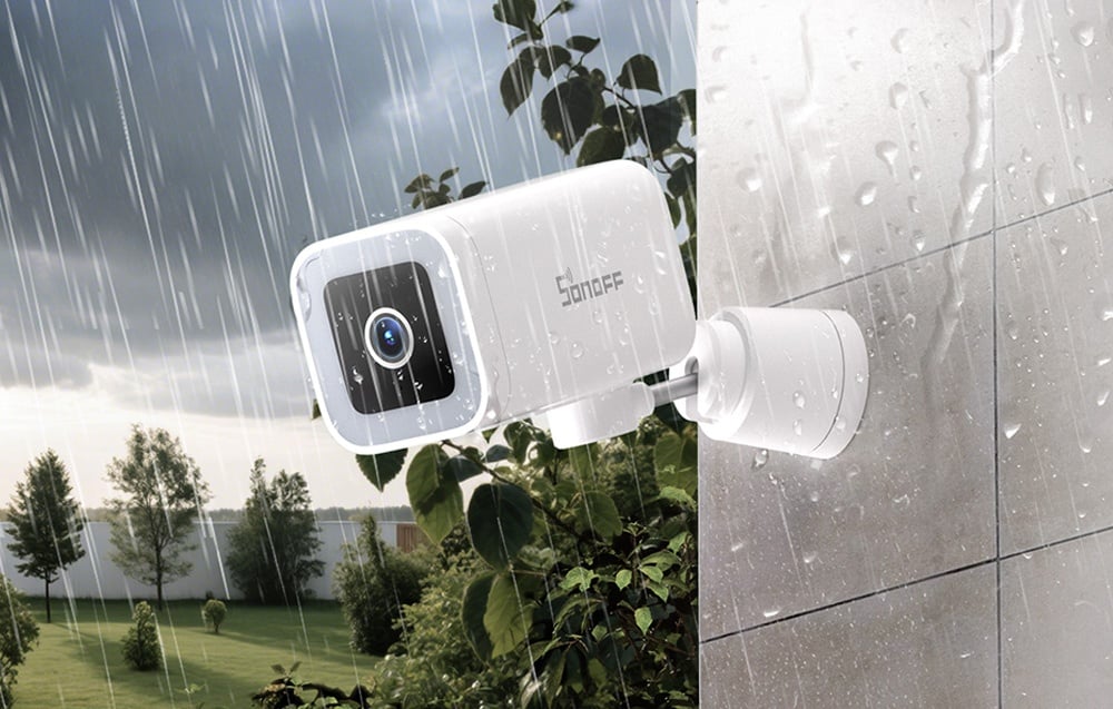 Biała kamera SONOFF na ścianie podczas deszczu z kroplami wody na obudowie i otoczeniu