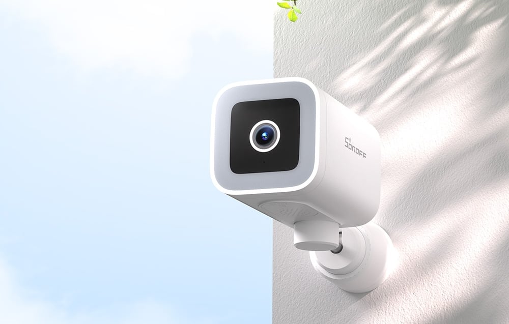 Biała kamera bezpieczeństwa SONOFF zamontowana na rogu białej ściany zewnętrznej