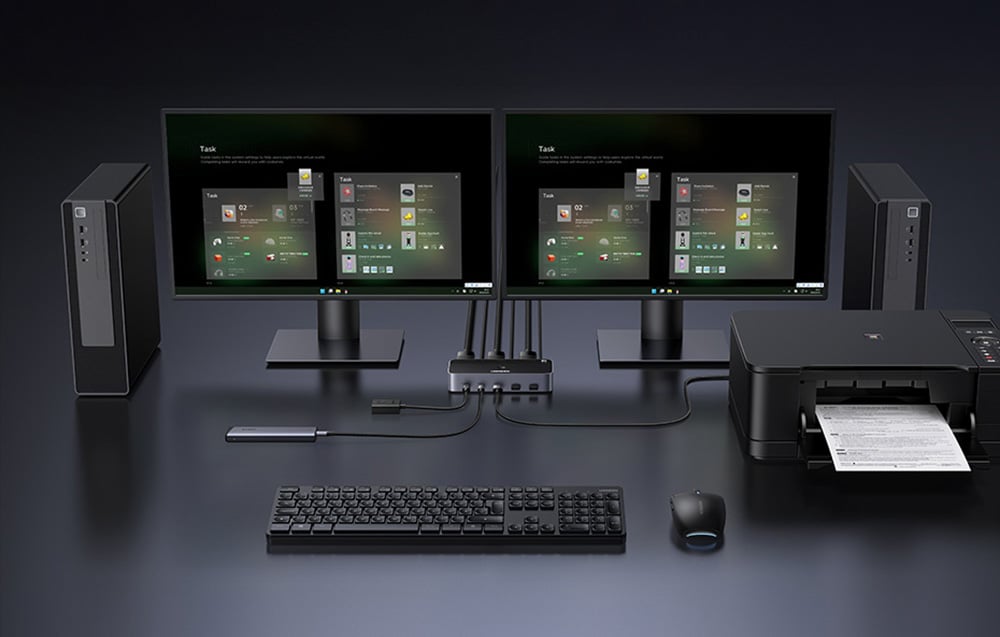 2 monitors and computers on a desk. There is also a keyboard, mouse, printer, switch, etc.