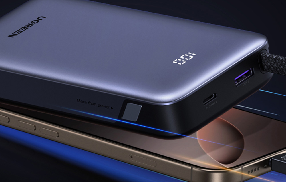 A gray Ugreen power bank and a smartphone lying next to each other.