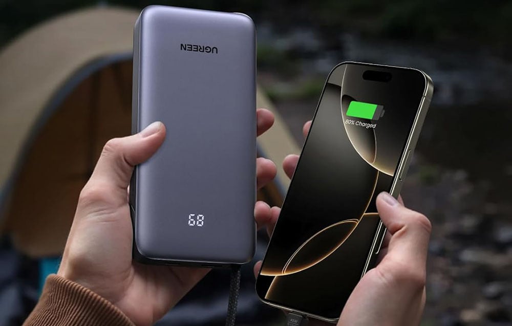 A smartphone and a gray Ugreen power bank with a display held in hands.