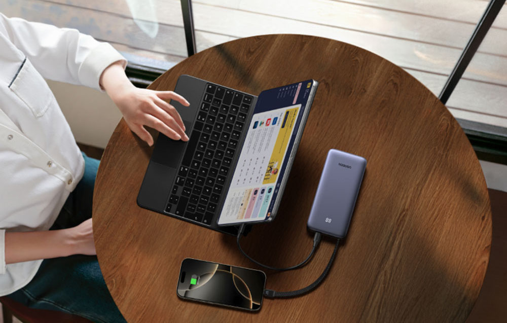 Power bank with a built-in cable connected to a laptop and smartphone.
