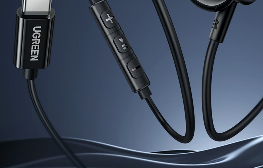 Close-up of the USB-C connector and control remote on the cable of black UGREEN headphones