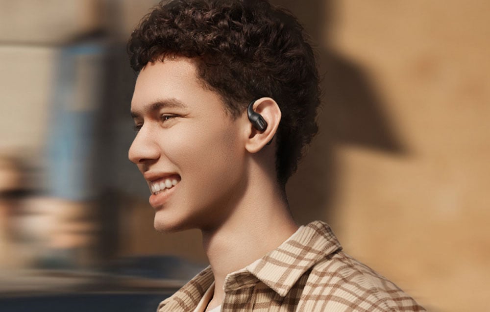 Uśmiechnięty mężczyzna na zewnątrz nosi czarną bezprzewodową słuchawkę douszną