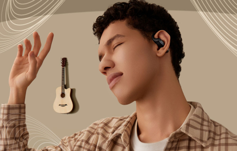 Mężczyzna z zamkniętymi oczami słucha muzyki w czarnej słuchawce dousznej, w tle gitara na ścianie