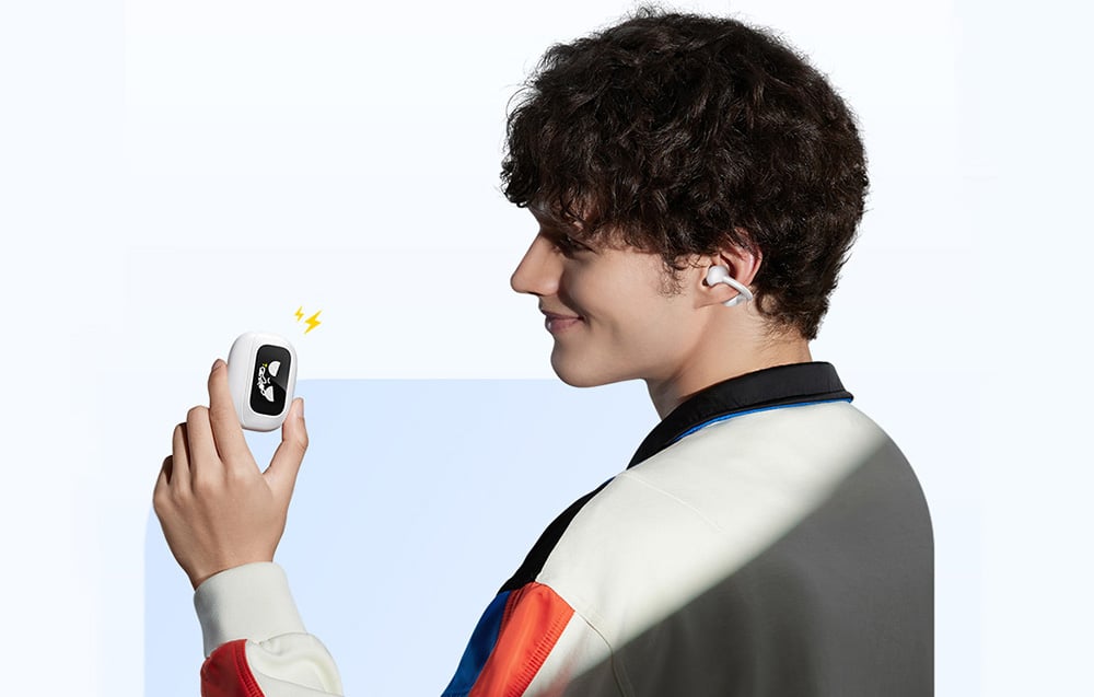 Mężczyzna z uśmiechem trzyma etui ze słuchawkami bezprzewodowymi i nosi jedną z nich w uchu