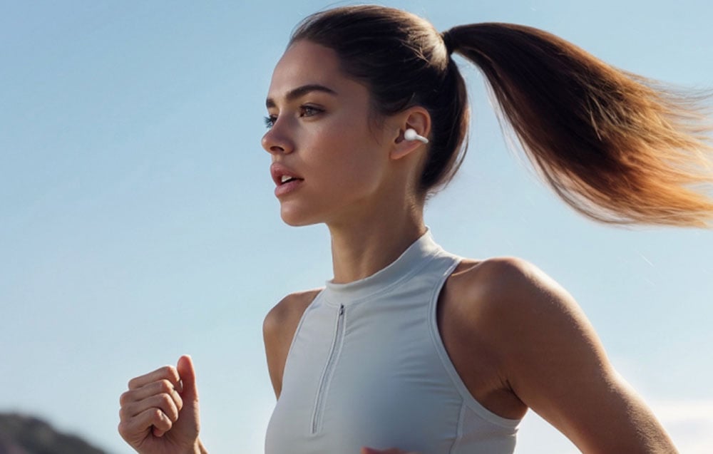 Kobieta biegnie na świeżym powietrzu w sportowym stroju i słuchawkach bezprzewodowych