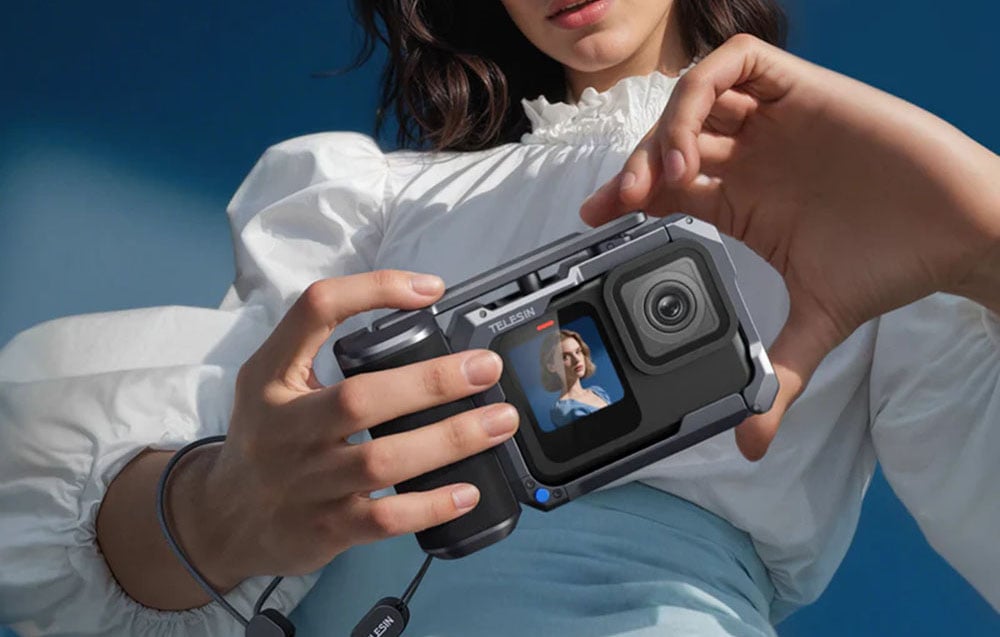 Frau in weißem Oberteil hält eine Sportkamera in der TELESIN-Hülle und schaut auf den Bildschirm mit der Vorschau