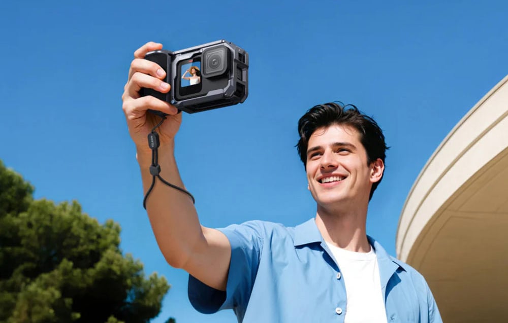 Mann lächelnd macht ein Selfie mit einer Sportkamera in der TELESIN-Hülle vor dem Himmel