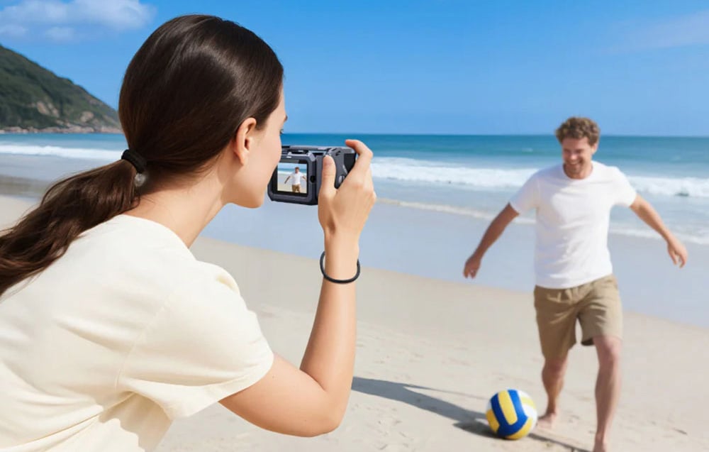 Frau am Strand filmt einen spielenden Mann mit einem Strandball mit einer Sportkamera in der TELESIN-Hülle