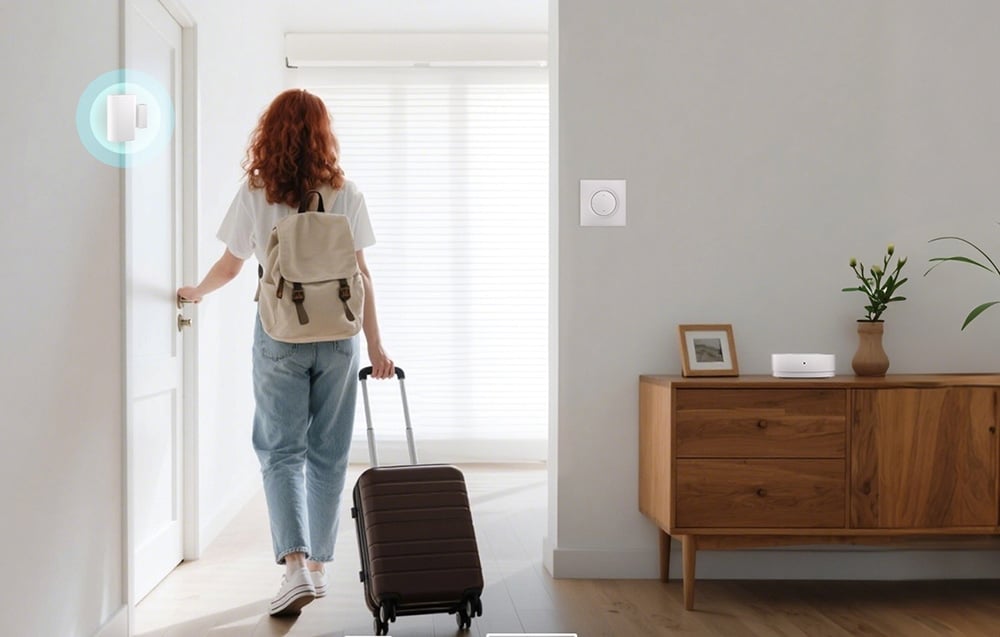 A woman with a backpack and a wheeled suitcase exits an apartment. A smart switch is mounted on the wall above a dresser.