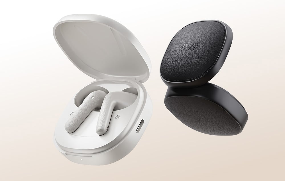 White and black wireless headphones in a case on a beige background.