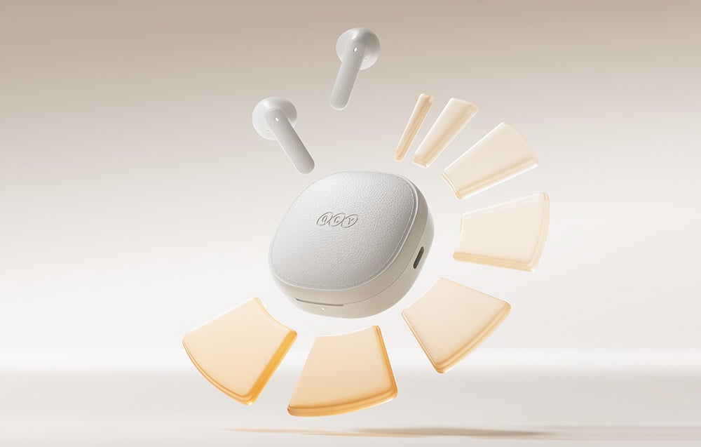 White wireless headphones with the QCY charging case on a light background.