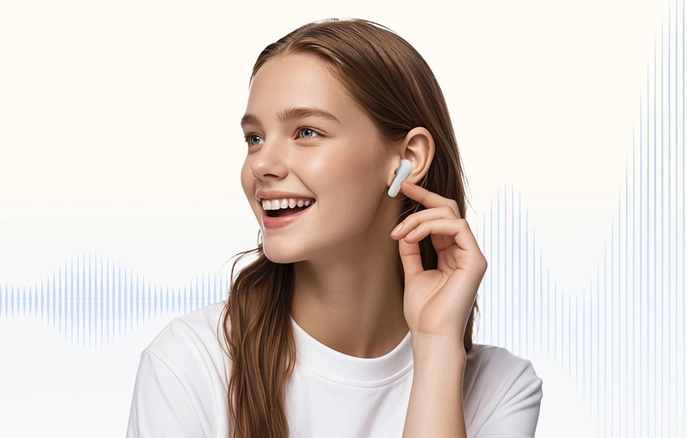 A smiling woman in a white shirt with a headphone in her ear.