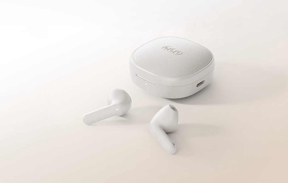 In-ear headphones next to the QCY charging case on a beige background.