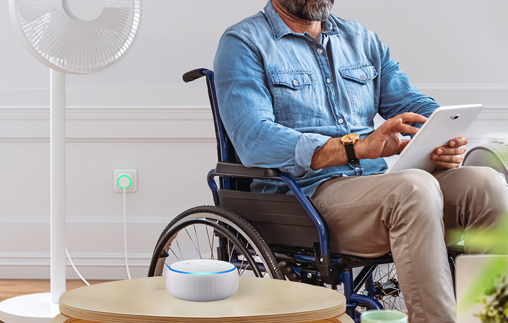 Man in a wheelchair using a tablet, with a fan connected to an intelligent socket with green backlighting in the background