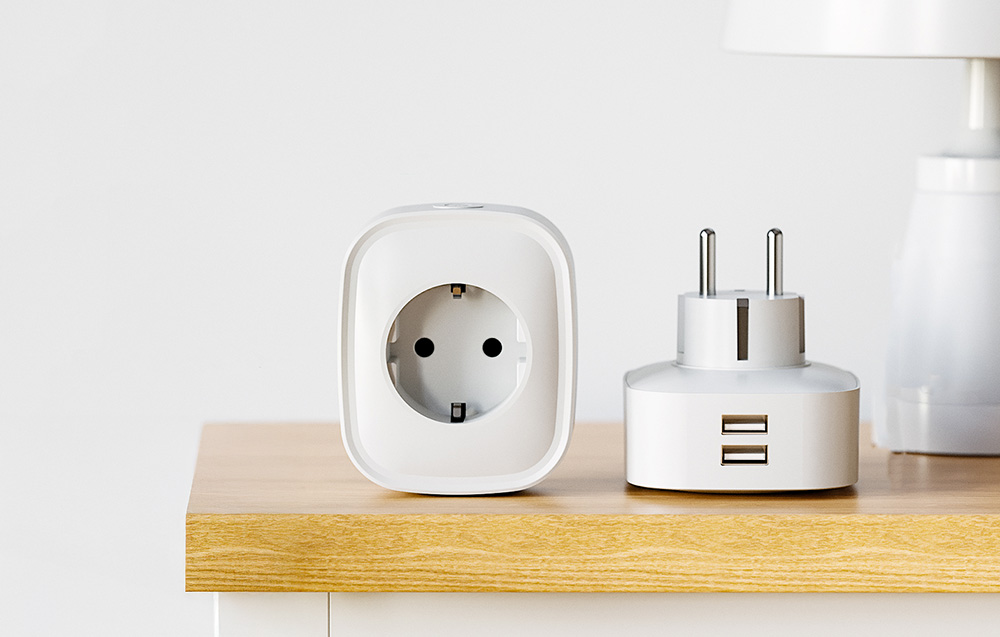 Two white adapters on a countertop – one with an electrical socket, the other with two USB ports