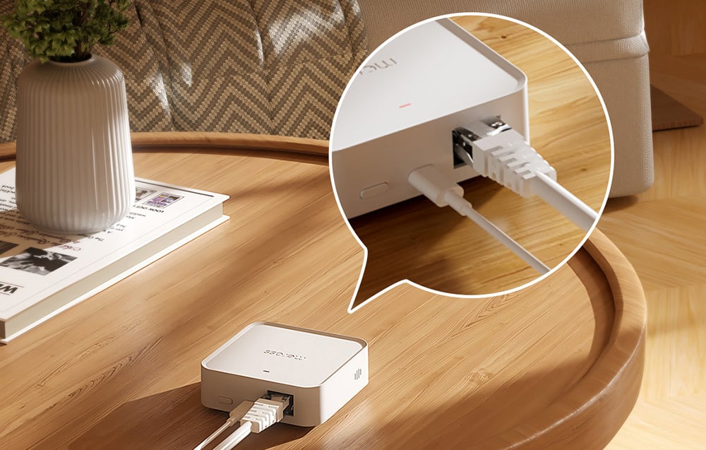 Inteligentny hub Meross na stoliku z podłączonymi kablami Ethernet i zasilania, zbliżenie na porty