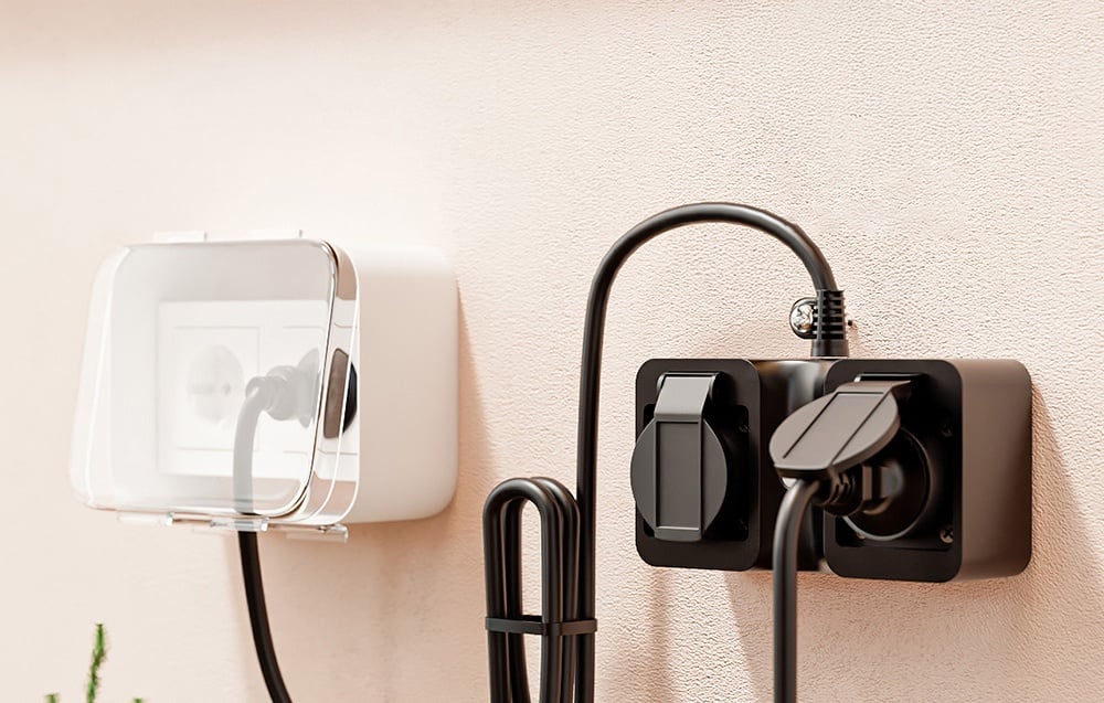 Two types of outdoor electrical sockets on the wall, one with a transparent cover, the other black with connected wires