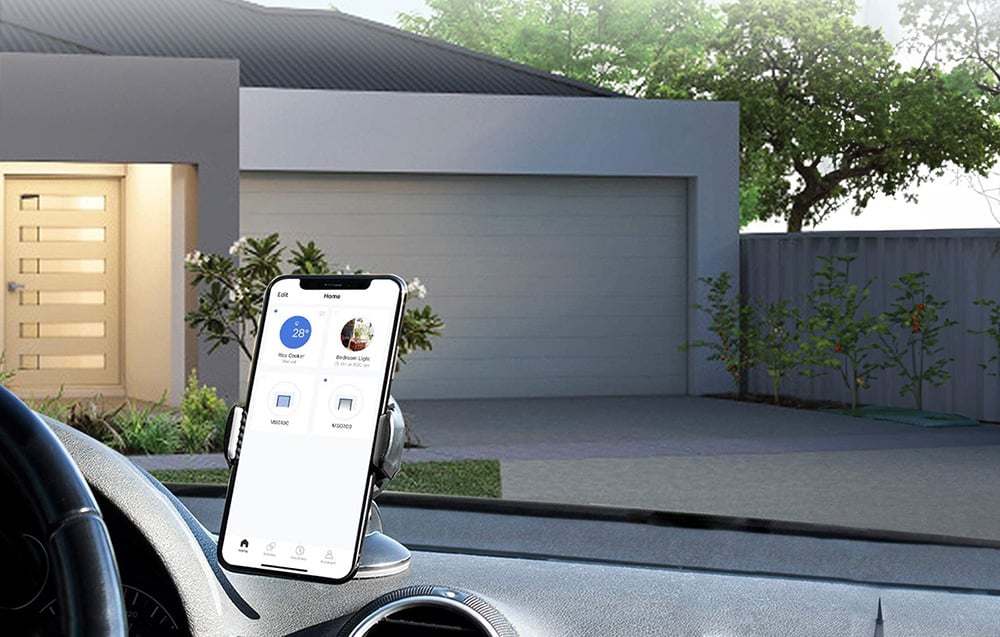 A smartphone mounted in a car shows a home device control app, against the backdrop of a closed garage door