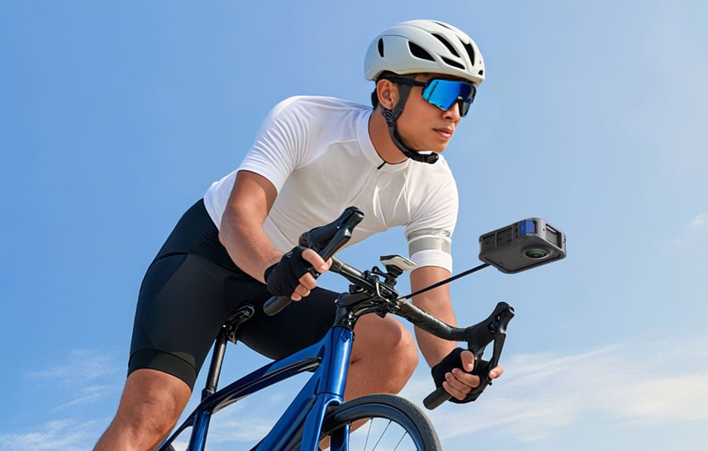 Radfahrer in weißer Kleidung, der auf einem Rennrad fährt, mit montierter Kamera in der TELESIN-Hülle am Lenker