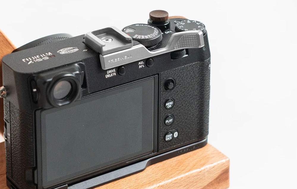 Fuji Film camera with a silver Freewell grip on a wooden table.