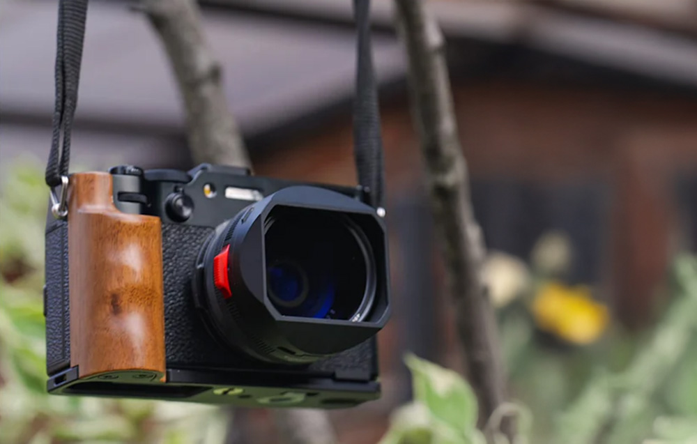 Camera with grip against a backdrop of plants.