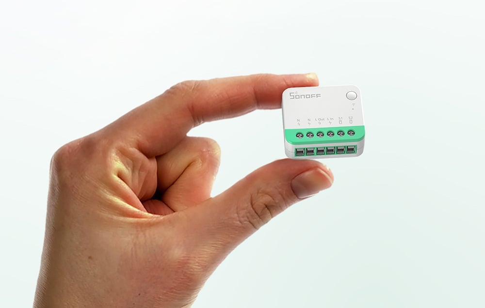 A person holding the compact Sonoff Mini Extreme module between their fingers