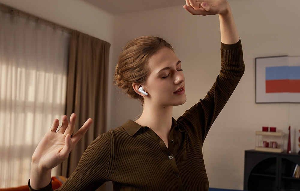 Dziewczyna z białymi słuchawkami w uszach tańcząca w pokoju