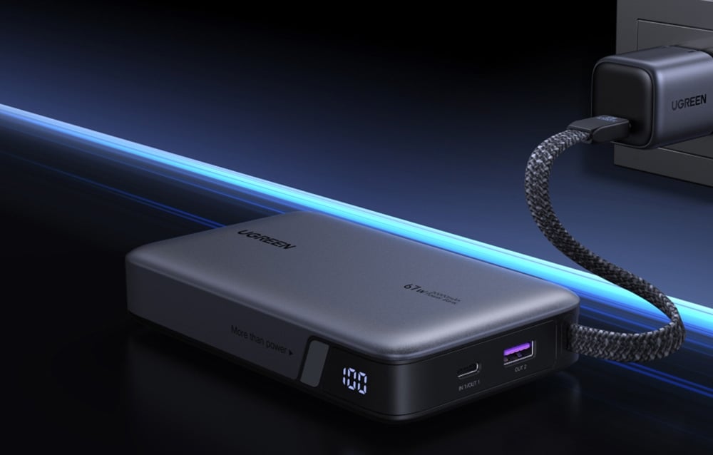 Grau Powerbank Ugreen, die an eine Steckdose auf einem dunklen Hintergrund angeschlossen ist