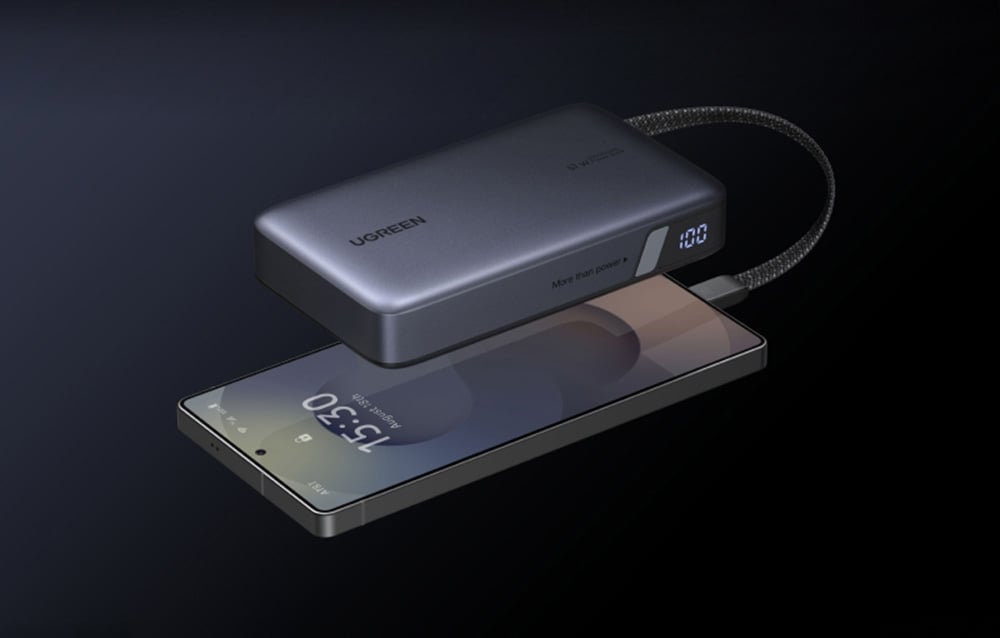 Smartphone, das an die graue Powerbank Ugreen auf einem dunklen Hintergrund angeschlossen ist