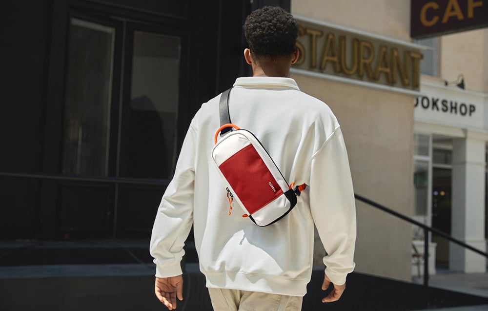 Rear view of a man in a white jacket with a waist bag in front of a restaurant and café entrance