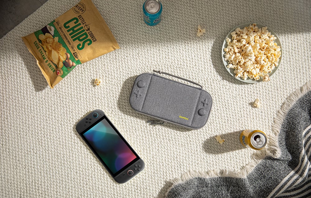 Console case lying on a carpet next to popcorn, chips, and drinks