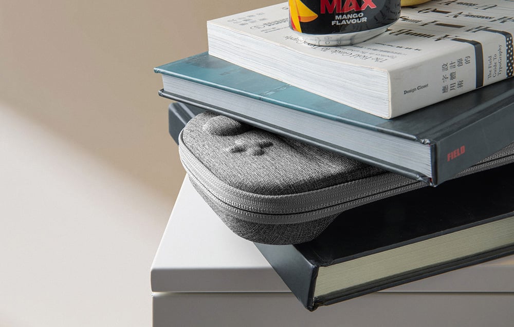 Gray console case arranged between books on a white shelf
