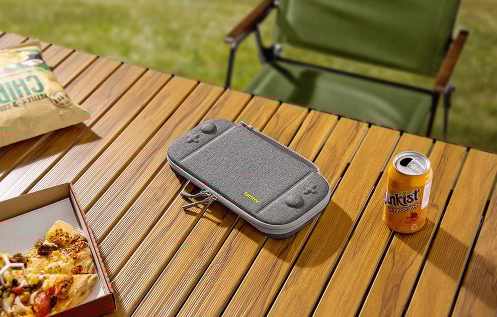 Console case on a wooden garden table with pizza and a drink